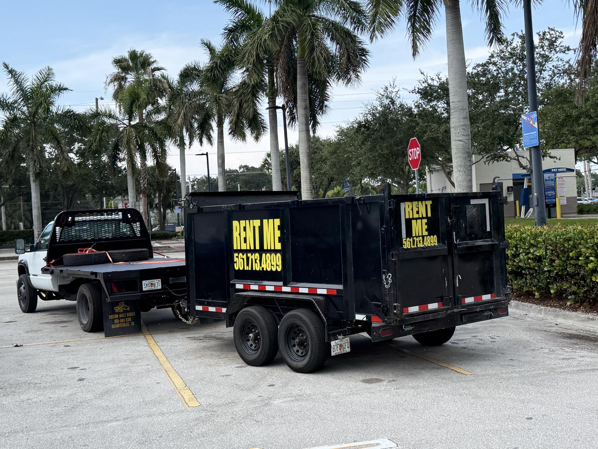 Safe USA Transport dump trailer with RENT ME 561.713.4899 signage hitched to a pickup truck